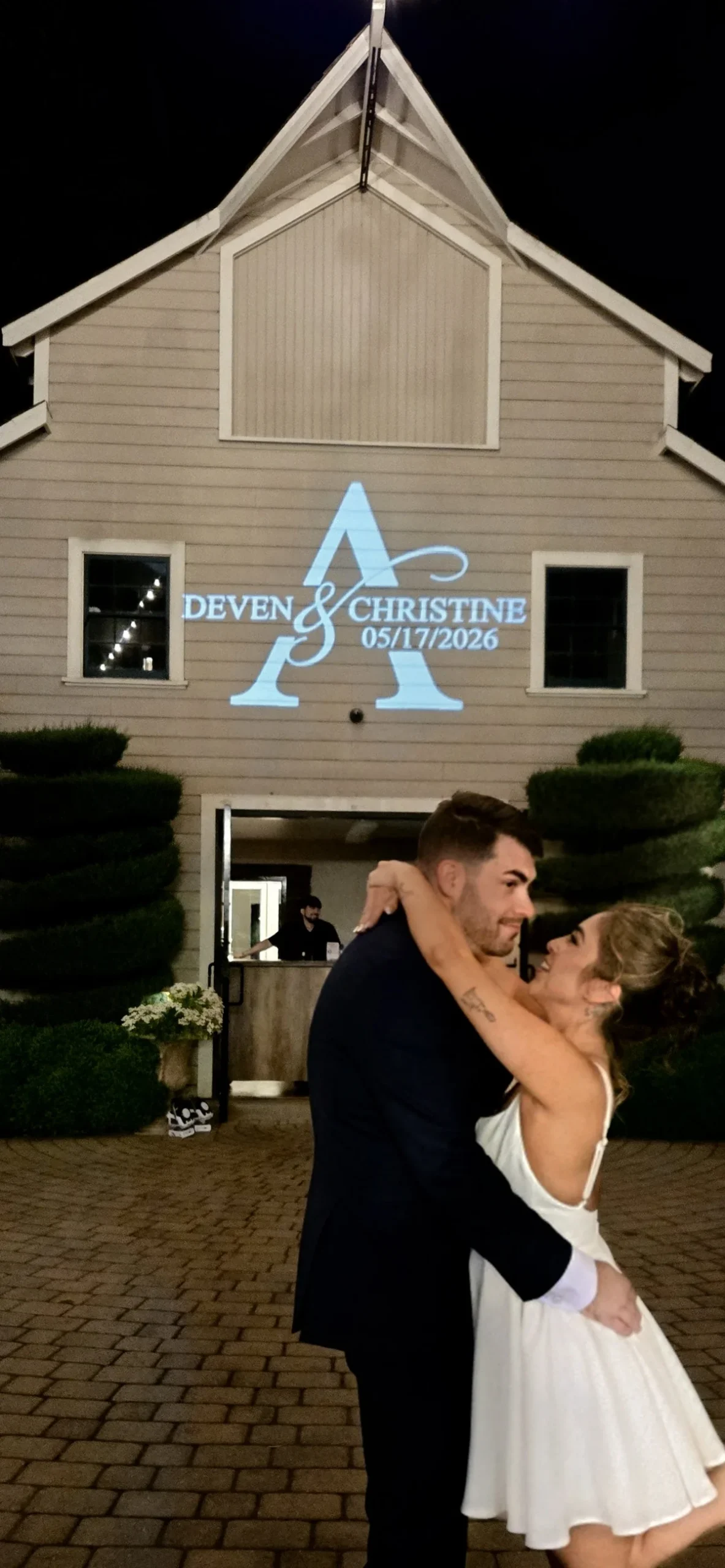 Bride and groom in front of a custom monogram projected on a barn wedding venue by J Crew Productions