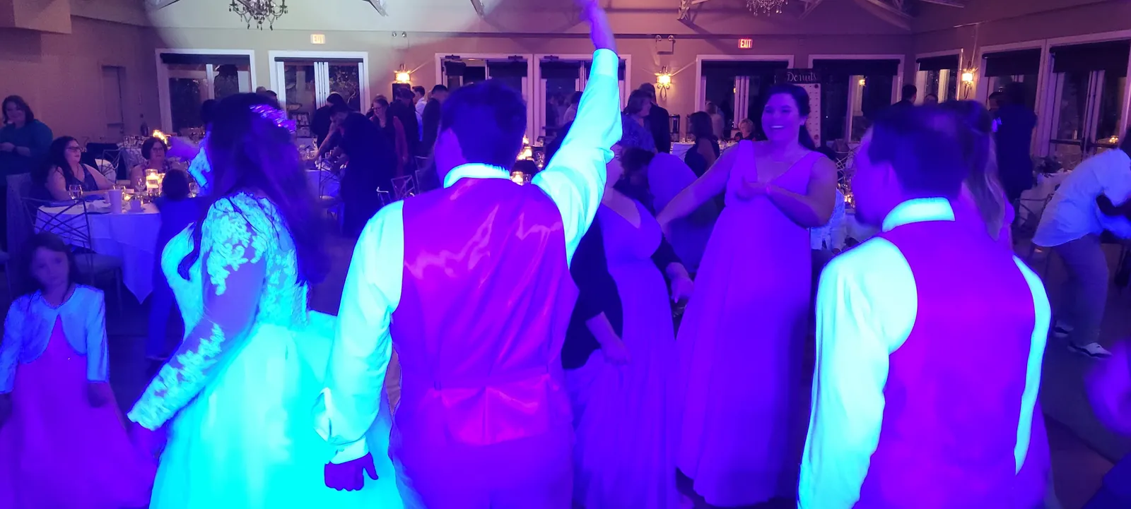Wedding guests with hands up on a purple-lit dance floor in Granite Bay, CA