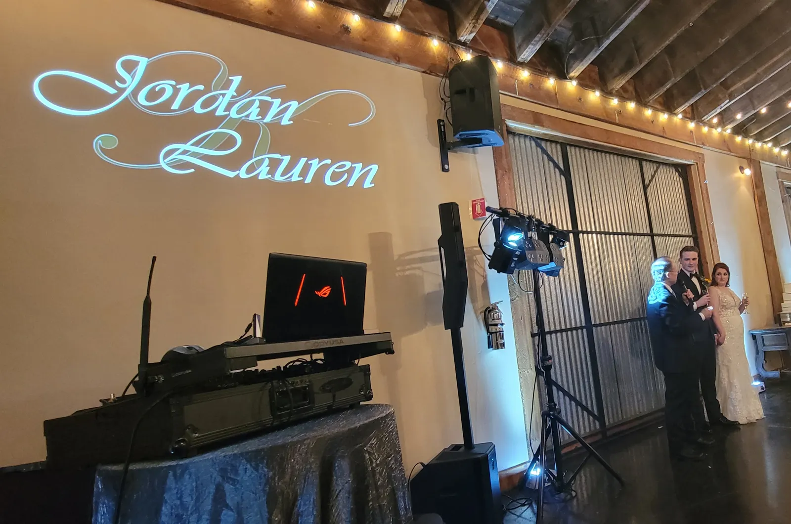Script name monogram projected on the reception wall during toasts, wedding DJ setup by J Crew Productions